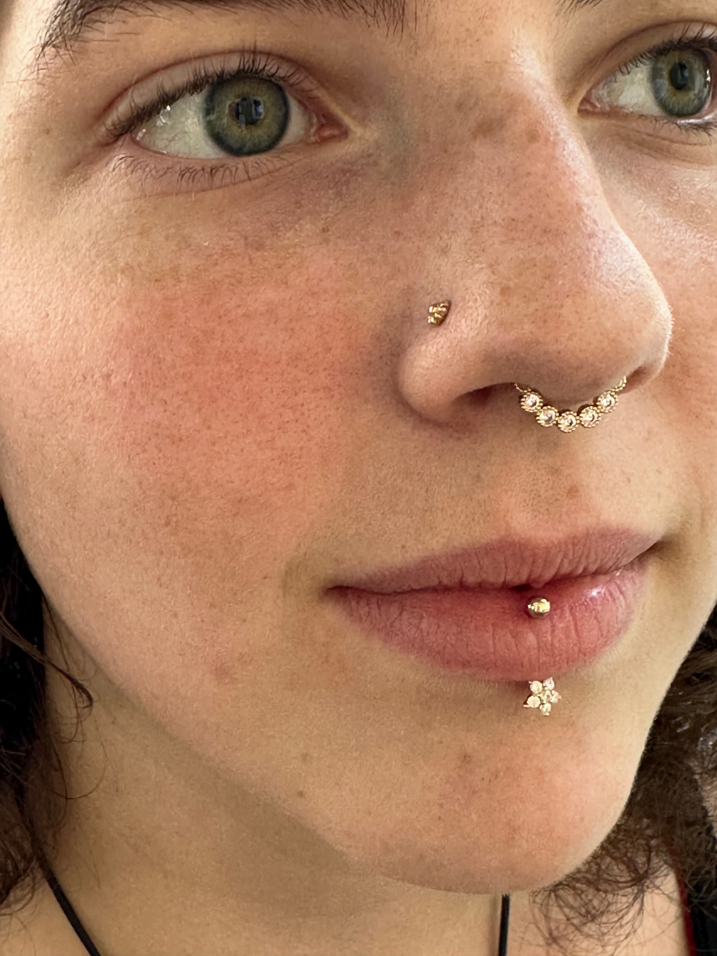 Client showing gold nose and lip piercing jewelry